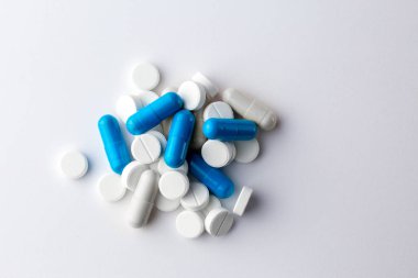 Kopya yazma yeri olan beyaz bir zemin üzerinde haplar. Bir insanı tedavi etmek için beyaz ve mavi haplar. Sağlık ve tıp konsepti. Bir avuç antibiyotik. Tıbbi hazırlıklar. Bir çocuğu tedavi etmek. Vitamin Kapsülleri