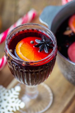 Tencerenin yanındaki güzel bardakta sıcak şarap. Bardakta sıcak içecek. Noel konsepti. Sıcak bir içecekle aile akşamı. Biz elma ve portakallı sıcak şarap pişiririz. Meyveli sıcak şarap