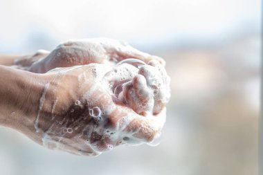 Bir adam ellerini sabunla yıkar. Köpüklü bir adamın elleri