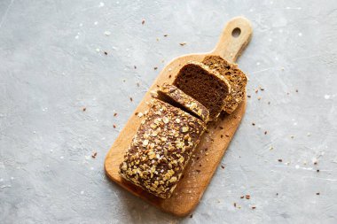 Sütlü tahtanın üzerinde dilimlenmiş ekmek. Lezzetli, ev yapımı tahıllı ekmek. Ev yapımı pişirme. Glütensiz hamur işleri. Sütlü siyah ekmek. Ev yapımı ekmek.
