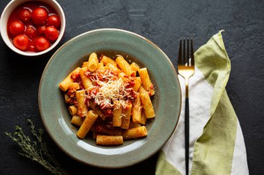 Lezzetli iştah açıcı domates soslu İtalyan makarnası, parmesan peyniri ve erişteli siyah bir masa. Üst görünüm, yatay. İtalyan pastası. Tavuk ve domates soslu makarna..