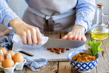 Fındık eziyor. Bir aşçı tahtada bir somunu bıçakla öğütür. Tahtada fındık var. Turta için tarçınlı, fındıklı ve kuru üzümlü dolma. Evde yemek pişir. Turta için gerekenler.