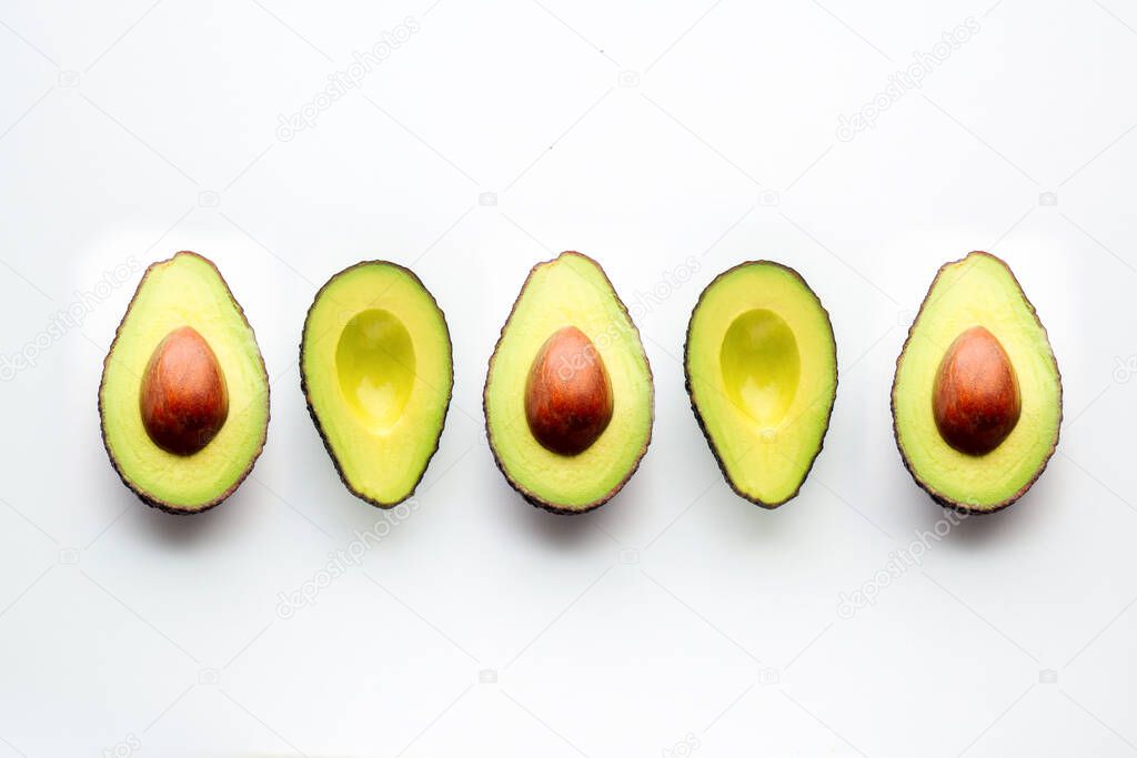 Avocado on a white background. Cut avocado lies in one line. Fruits scatter on the table. Ingredient for proper nutrition. Half an avocado. Insect avocados. Beautiful background, top view 
