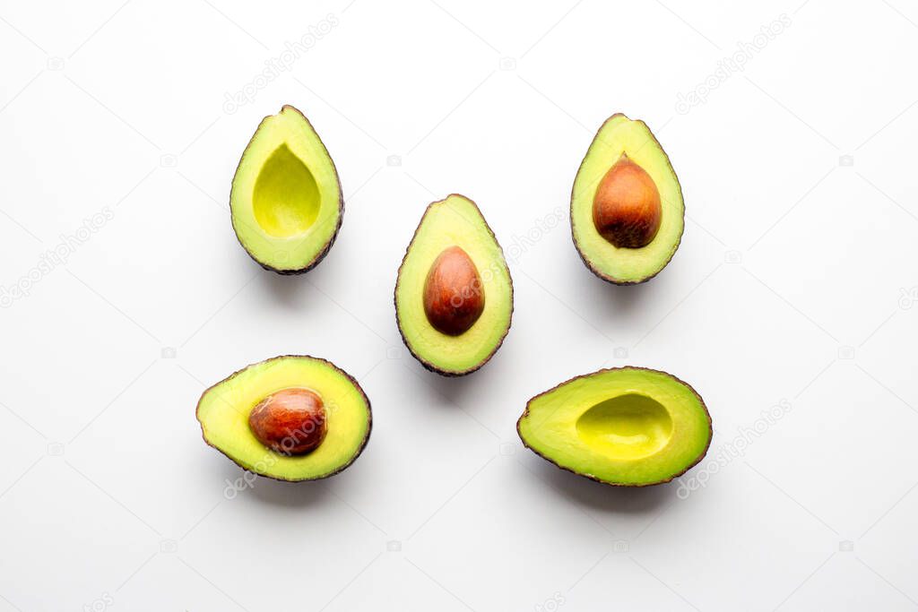 Avocado on a white background. Cut avocado lies in one line. Fruits scatter on the table. Ingredient for proper nutrition. Half an avocado. Insect avocados. Beautiful background, top view 