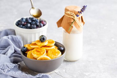 Mini gözlemeler şurup serpiştirilmiş. Şurup kreplerin üzerine dökülüyor. Kasede yaban mersinli mini gözleme. Akçaağaç şurubu krepleri. Güzel, lezzetli, parlak bir kahvaltı. Vejetaryen yemeği. Yemek trendi. Süt Günü. 