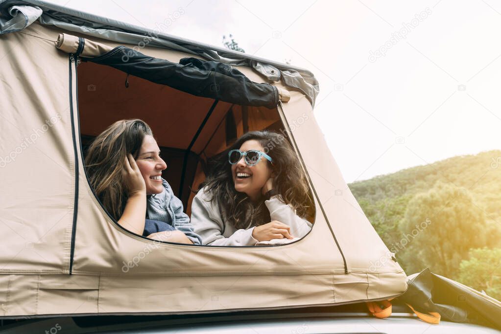 Two women talking in their tent while camping in the wild