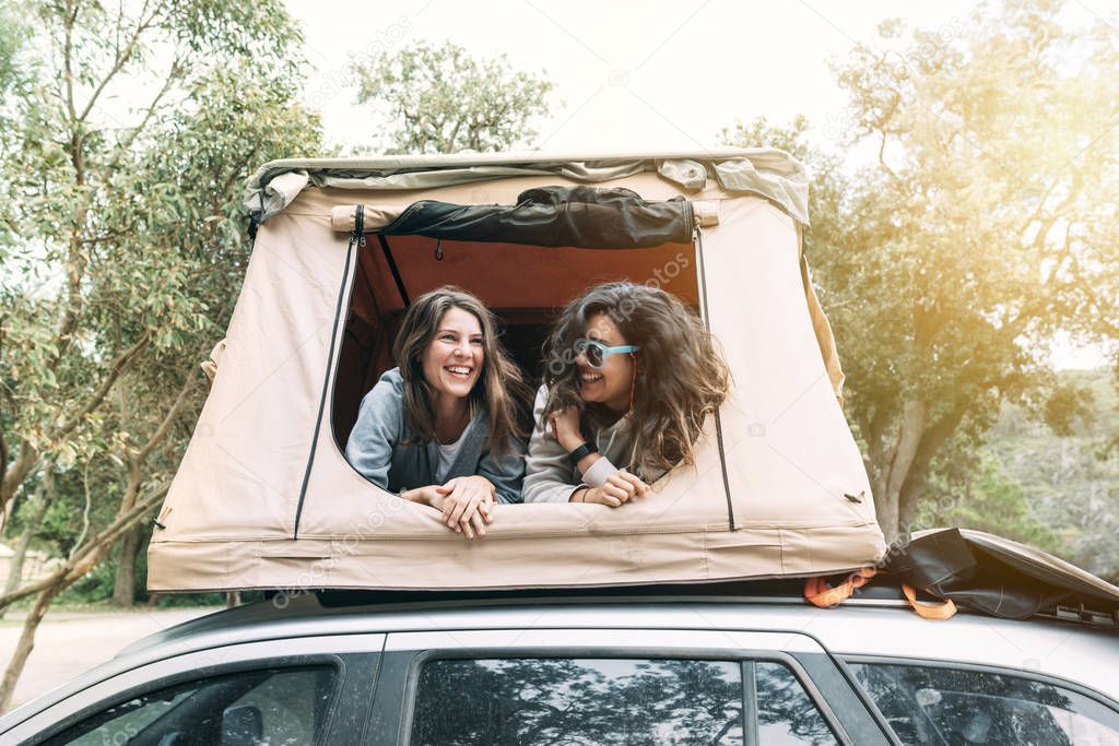 Two young girls laughing and having fun in their rooftop tent