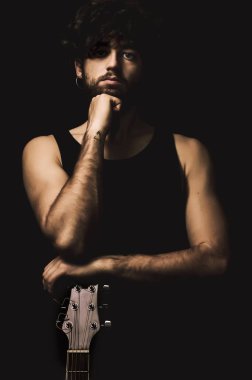 Mavi gözlü ve gitarlı genç bir modelin stüdyo portresi.