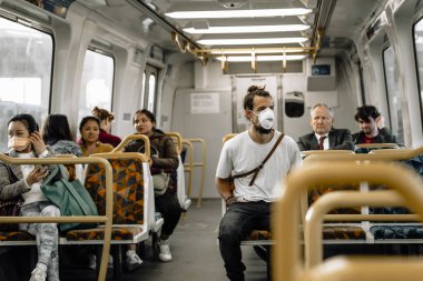 Genç bir virüs metroda koronavirüs enfeksiyonunu önlemek için maske takar.