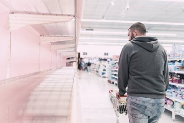 Coronavirus yüzünden market alışverişi yapan bir adam. Süpermarkette Coronavirus veya Covid-19 virüsü yüzünden tuvalet kağıdı, kağıt, havlu, mendil ve mendil kalmamış..