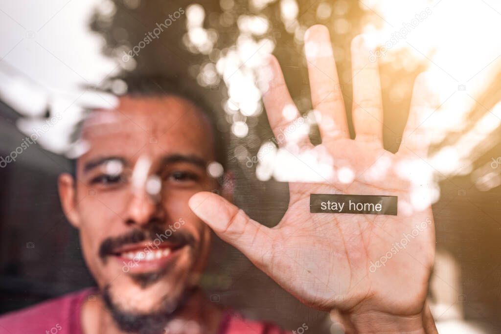 Stayhome message printed in a young man's hand. He is enjoying his time at home during Coronavirus lockdown and wants to prevent the spread of Covid 19 in countries such as United States, UK or France