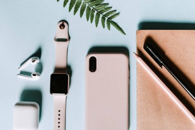 Pembe ve mavi düz ofis, akıllı telefon, akıllı seğirme, kulaklık, not defteri, kalem gibi modern cihazlar. Pembe ve mavi renkler. Yazılacak metin boşluğu. Üretkenliği arttırmak için minimalist stil