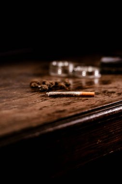 Arka planda ot tomurcukları ve öğütücüyle sigara içmeye hazır bir marihuana sarması. Esrar eğlence amaçlı bir ilaç ve aynı zamanda tıbbi bir terapi. Adı hamamböceği, esrar, yağ......