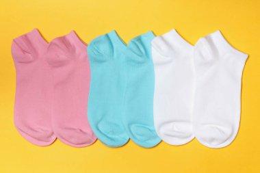 Sarı arka planda beyaz, pembe, mavi çoraplar.