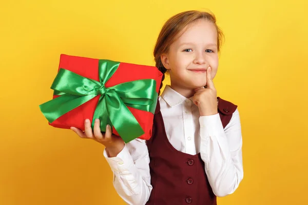 Il bambino tiene una scatola con un regalo e sogni. Carino bambina su uno sfondo giallo — Foto Stock