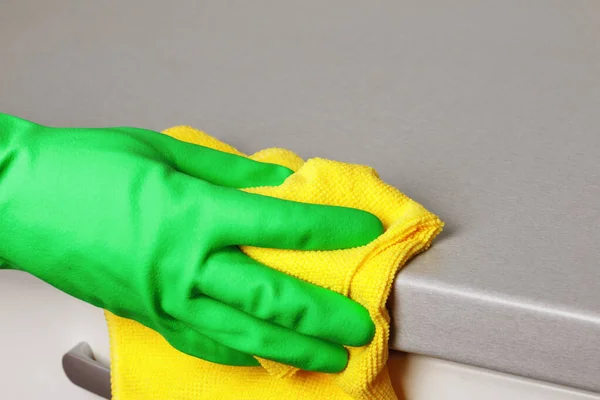 Primer plano de una mano en un guante protector sosteniendo una servilleta y limpiando una encimera. Limpieza de la cocina — Foto de Stock