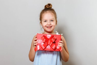 Hediye kutusuyla küçük şirin bir kızın yakın plan portresi. Gri arka plandaki bebek