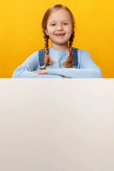 Šťastné veselé dítě drží prázdný bílý prapor prostoru na žlutém pozadí — Stock fotografie