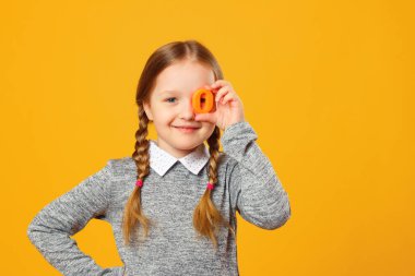 Sarı arka planda neşeli küçük bir kızın portresi. O harfi liseli kızda. Eğitim kavramı