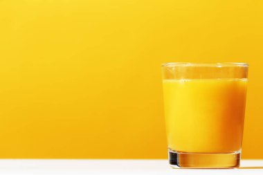 Sarı bir arka plan üzerine portakal suyu bir bardak