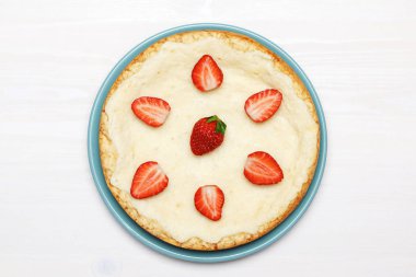 Beyaz arka planda çilekli klasik bir cheesecake. Üst görünüm