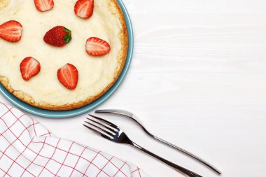 Beyaz ahşap arka planda çilekli cheesecake. Metin için üst görünüm ve kopyala