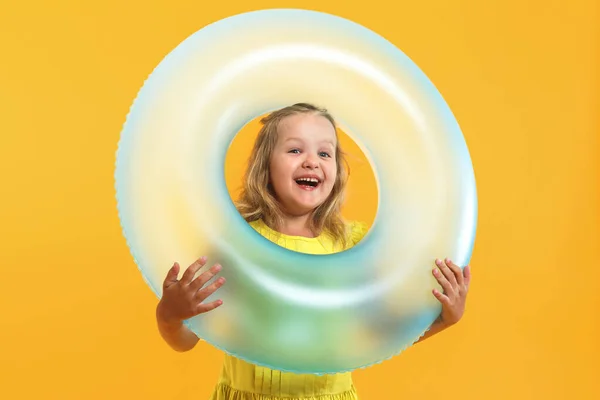 Retrato de uma menina criança feliz em um vestido com um anel de natação em um fundo amarelo colorido. Conceito de férias — Fotografia de Stock