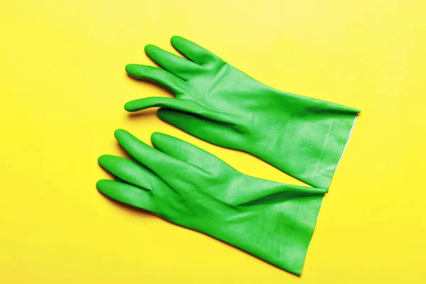 黄色の背景にゴム製の緑の手袋。トップ表示 — ストック写真