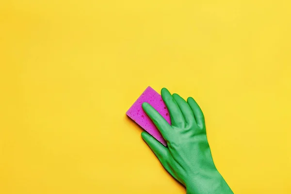 Sarı arka planda pembe süngeri olan lastik koruyucu eldivenli bir el. Temizlik kavramı — Stok fotoğraf