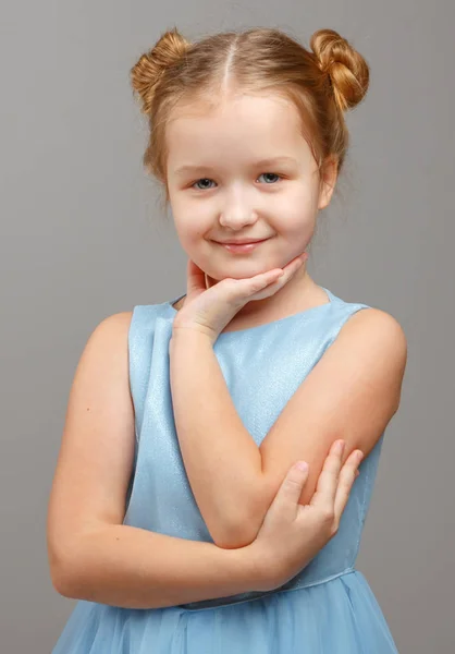 Портрет милої маленької дівчинки в блакитній сукні на сірому фоні — стокове фото