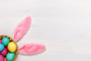 Beyaz arka planda sepetin içinde tavşan kulakları ve renkli yumurtalar. Paskalya konsepti. Boşluğu kopyala