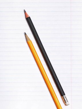 Çizgileri olan bir kağıt defter yaprağıüzerinde siyah ve sarı grafit kalemler vardır. Kopya alanı. Eğitim kavramı. Düz yüzey