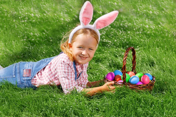 Cute little girl child with basket on green grass in the park. Easter Egg Hunting Concept — Stock Photo, Image