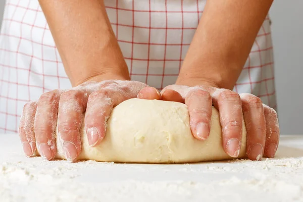 Vrouw kneedt rauw vers deeg met handen op tafel — Stockfoto