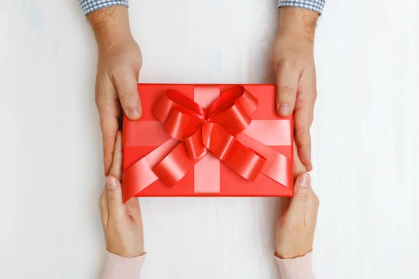 Közelkép egy férfi kezéről, amint egy piros dobozt ad ajándékba egy nőnek.. — Stock Fotó