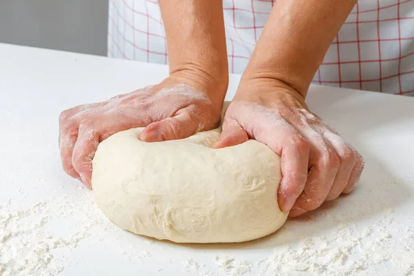 Woman kneads raw fresh dough with hands on the table — Stock Photo, Image