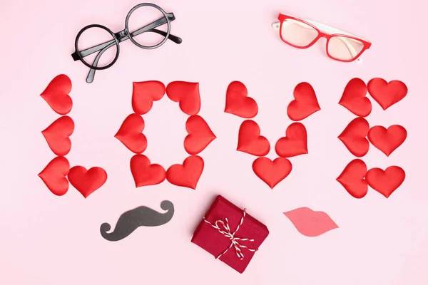 Día de San Valentín con corazones rojos regalo letras amor accesorios de la fiesta sobre un fondo rosa. Vista superior plano laico —  Fotos de Stock