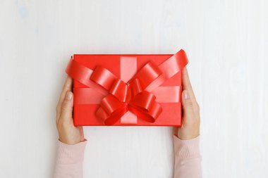 Masada kırmızı bir kutuya hediye veren bir kadının yakın çekimi. Üst Manzara. Sevgililer Günü ve Noel kutlaması kavramı
