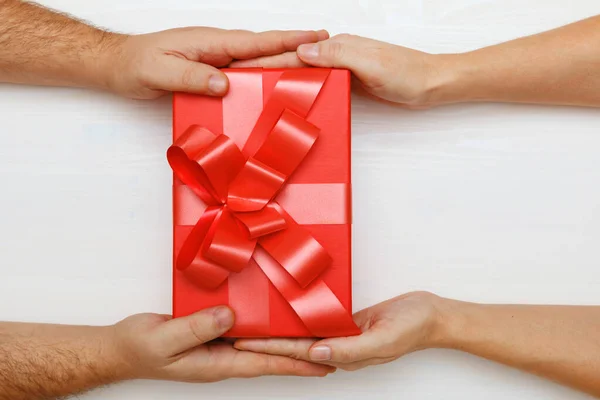 Primer plano de la mano de un hombre dando una caja roja con un regalo a una mujer. Vista superior. Concepto de Día de San Valentín y celebración de Navidad —  Fotos de Stock