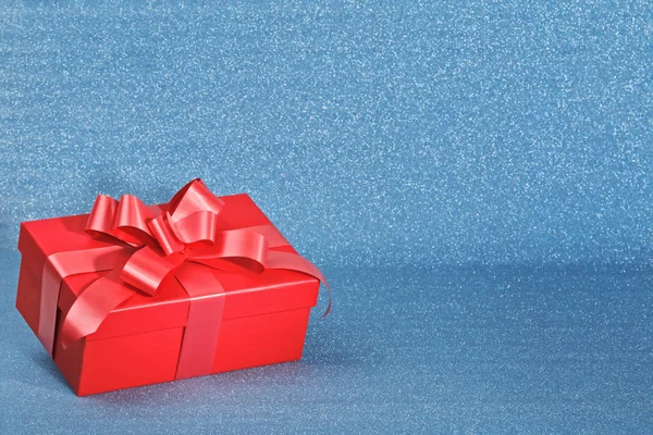 Primer plano de una caja roja con un regalo sobre un fondo azul brillante con espacio para copiar. Concepto de celebración del día de San Valentín — Foto de Stock