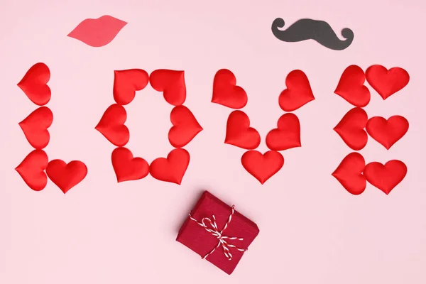 Día de San Valentín. Fondo rosa con letras de corazones rojos regalo labios bigote. Vista superior plano laico —  Fotos de Stock