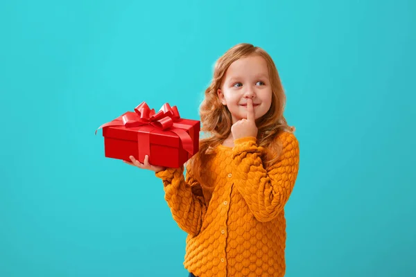 Ritratto di una bambina con un maglione lavorato a maglia su un retro ciano — Foto Stock