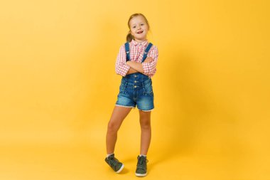 Mutlu küçük kız sarışın sarı duvarın karşısında duruyor.