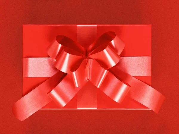 Close-up de uma caixa com um presente amarrado com um arco. Vermelho no backgr vermelho — Fotografia de Stock