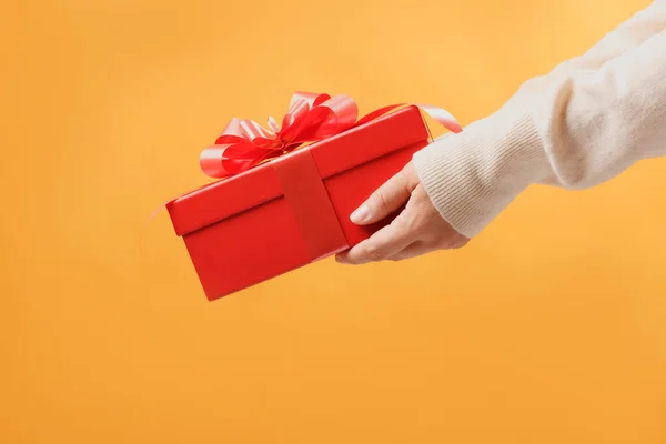 Close-up partial view of man in sweater holding red gift box on — 스톡 사진