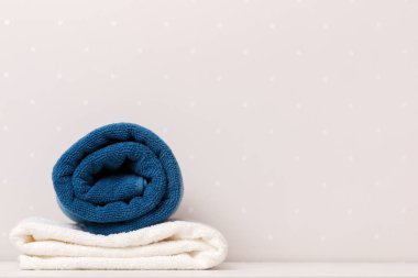 Mavi ve beyaz havluların yakın çekimi açık renkli duvarların arka planına karşı bir masanın üzerinde duruyordu.
