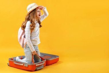 Küçük bir kız bir bavulun içinde oturur ve sarı bir arka planda uzaklığa bakar. Çocuk seyahat, yolculuk, macera, rahatlama hayalleri kurar..