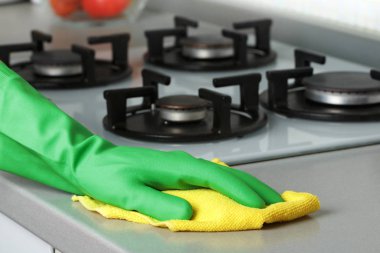 Koruyucu eldivenli, peçeteli bir elin yakın çekimi. Tezgahları yıkıyorum. Mutfağı temizliyorum..