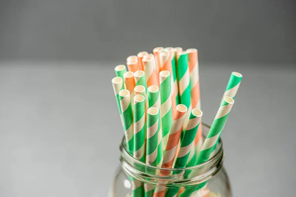 Paper straws in a jar in front of a grey background.