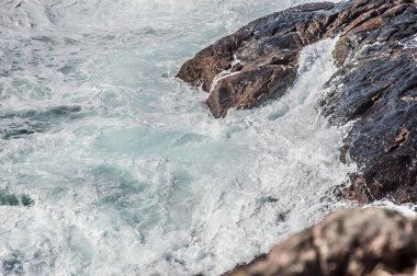 Dalgalar kırılıyor, beyaz köpük oluşturuyor..